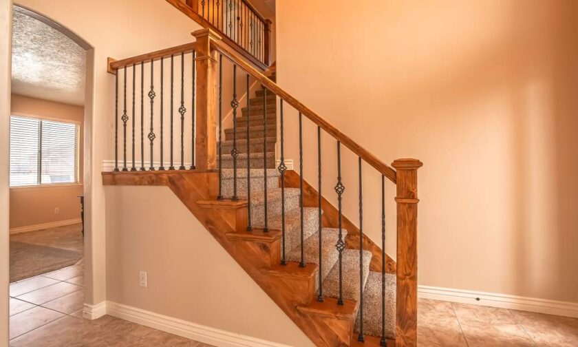 A home with a beautiful hardwood handrail, constructed to protect the family. The stairs are carpeted.